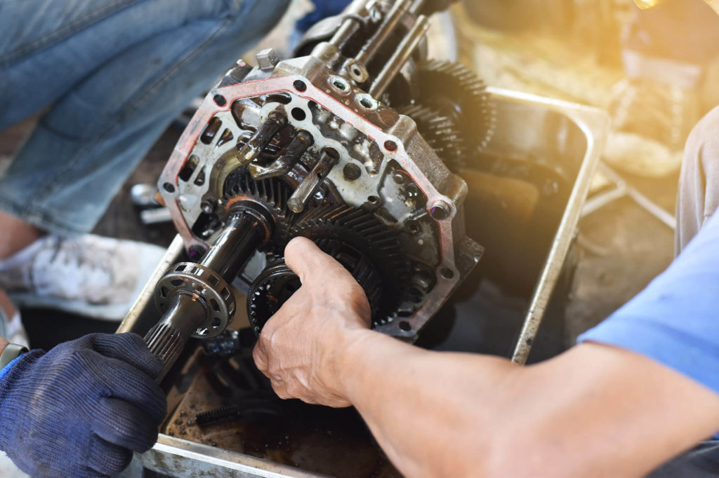 Mechanic checks and repairs the automobile transmission system.